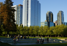 Improving Bellevue’s Grand Connection: Part 2 – Downtown Park to Bellevue Transit Center A photo of amphitheater style seating in a park with people sitting in the grass and tall modern buildings in the backdrop.