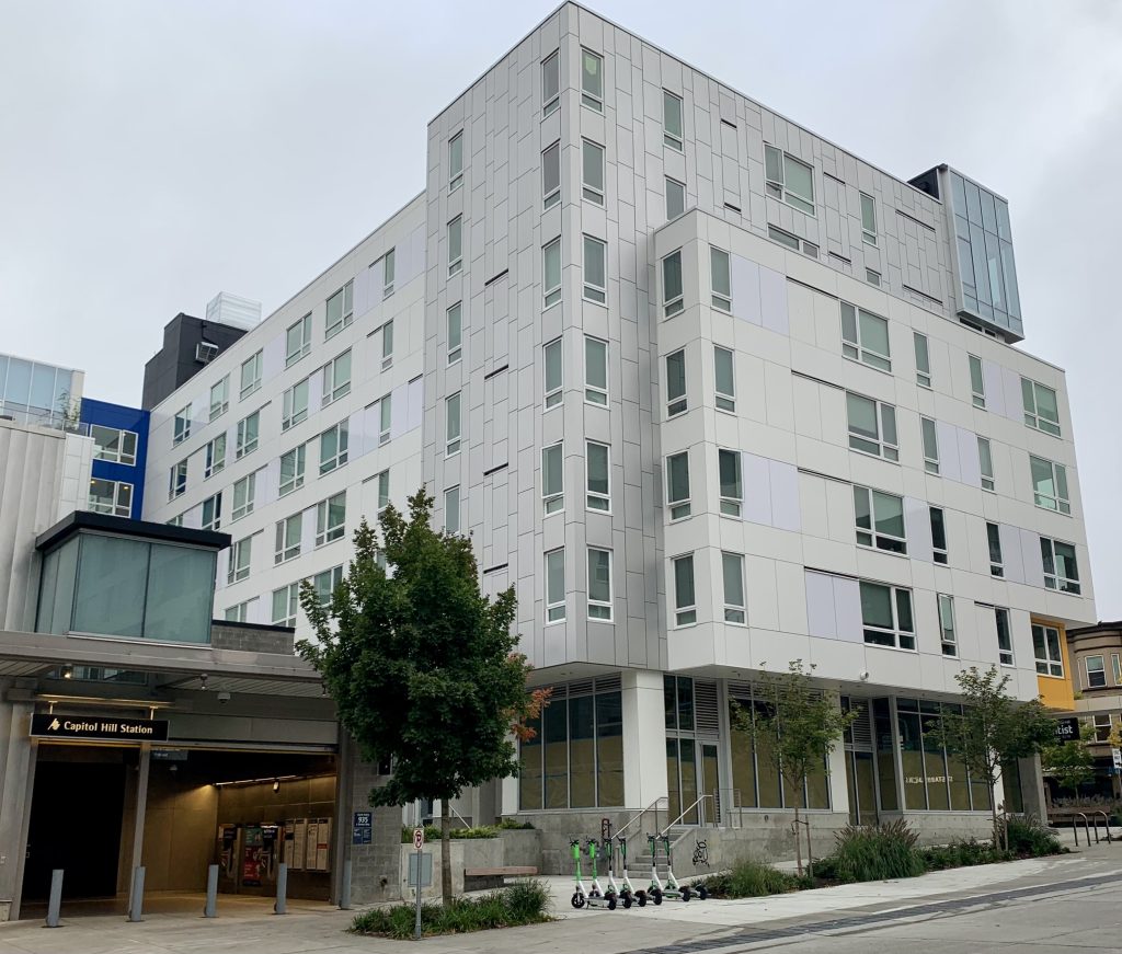 a photo of a six story apartment building constructed next to a light rail station in Capitol Hill