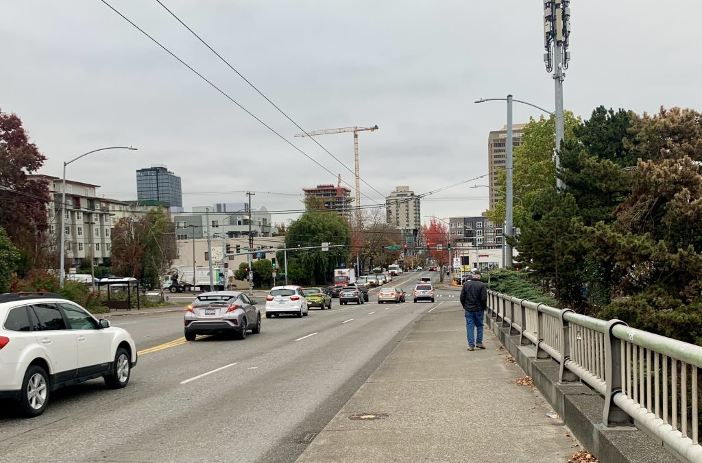 A photo of a sidewalk next to a busy roadway.