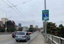 SDOT Drops Protected Bike Lane from NE 45th Street Bridge Plans, Citing Traffic Impacts A photo shows a sidewalk next to a roadway with cars. A sign says North Interstate 5.