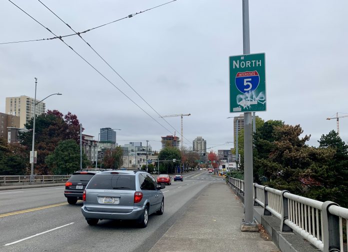 A photo shows a sidewalk next to a roadway with cars. A sign says North Interstate 5.