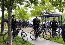 Councilmembers Spar Over Police Staffing Incentives, Poll Shows Broad Support for Addressing Root Causes of Crime Three bike-wielding cops form a barricade around a sweep with a large contingent of officers behind