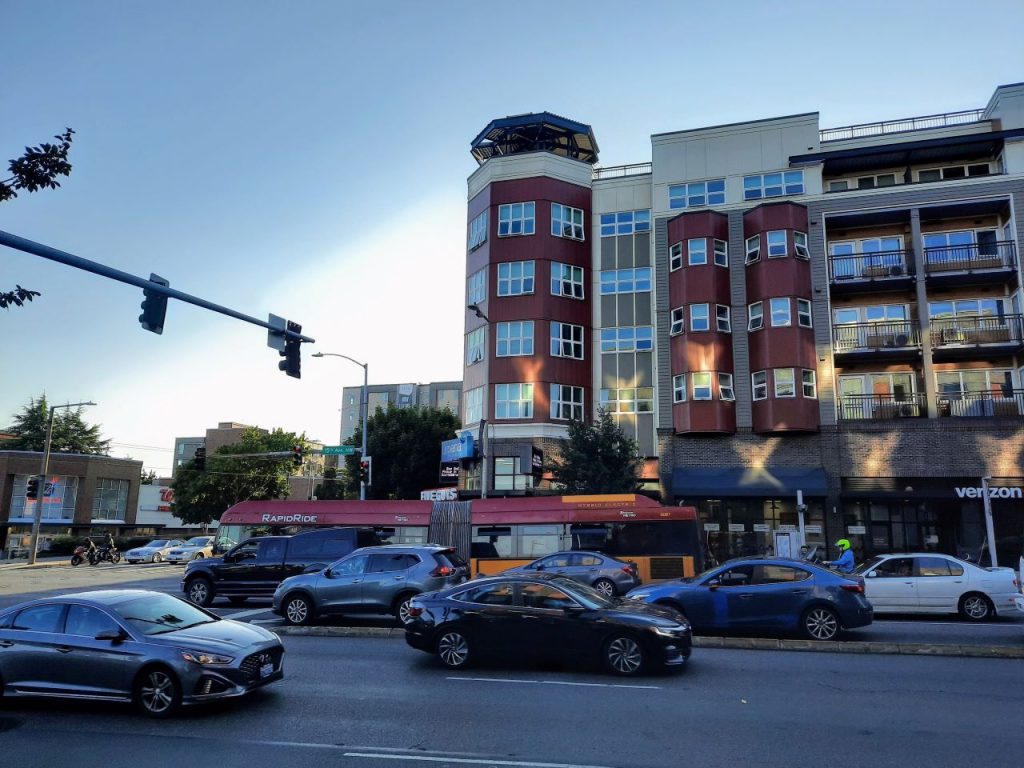 A busy six lane road with a RapidRide bus on the outside lane.