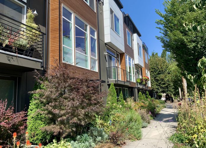 A photo of townhouses with lush shrubs and trees.