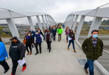 John Lewis Memorial Pedestrian Bridge Partially Mends Freeway Gash in Northgate A photo of people walking on a pedestrian bridge over Interstate 5.