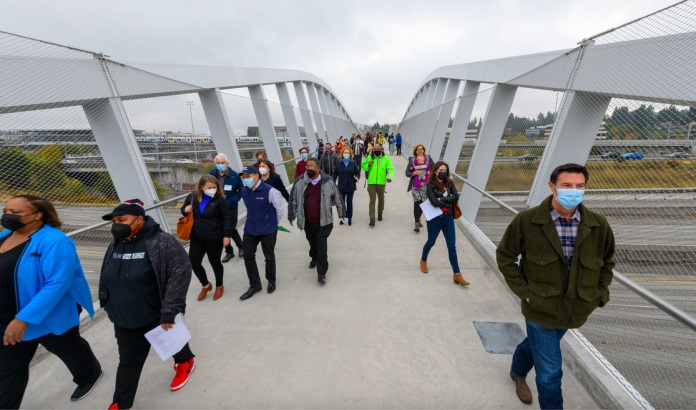 A photo of people walking on a pedestrian bridge over Interstate 5.