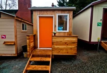 Advocates Debate Tiny House Villages’ Role in Reducing Homelessness A photo of a tiny house with an orange door.