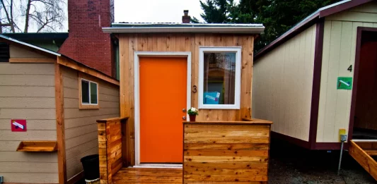 A photo of a tiny house with an orange door.