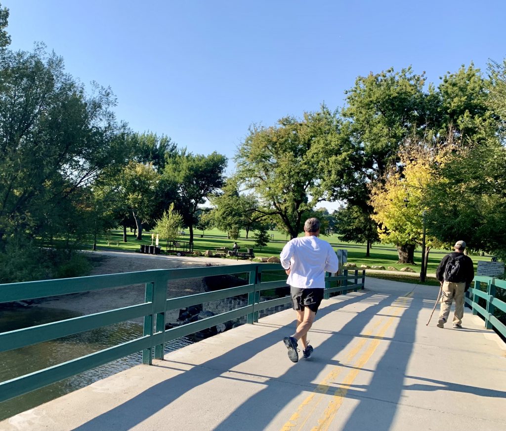 A photo of a pedestrian and bike bridge going over the Boise river with people running and walking. 