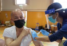 Vaccination Surge Shows Employee Mandates Work A health worker vaccinates a man wearing a face mask in a gymnasium.