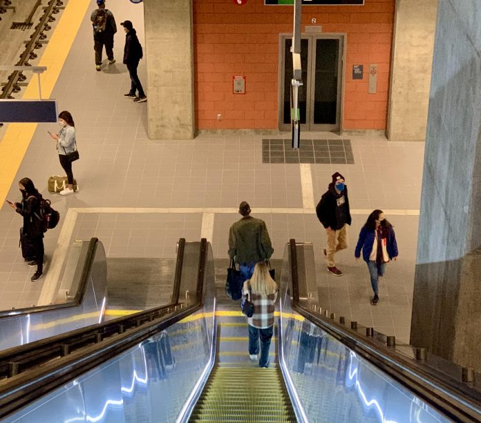 link light rail roosevelt station looking down escalator A photo of an illuminated escalator leading down to a light rail platform.