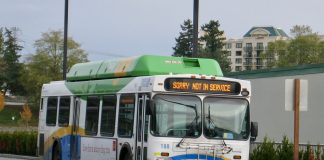A white, blue, and green bus runs with a not in service sign.