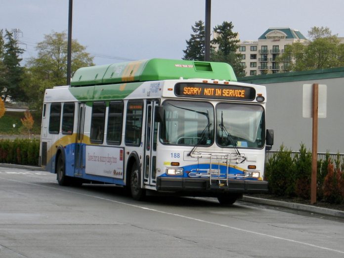 A white, blue, and green bus runs with a not in service sign.