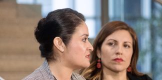 Head shot photo of two women in professional attire at a microphone.