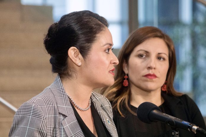 Head shot photo of two women in professional attire at a microphone.