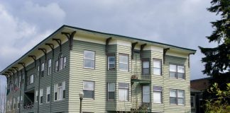A photo of a light green gray three story apartment building.