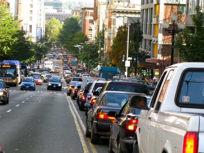 A photo of backed up car traffic on the right side of the road. Cars are approaching on the left side of the road.