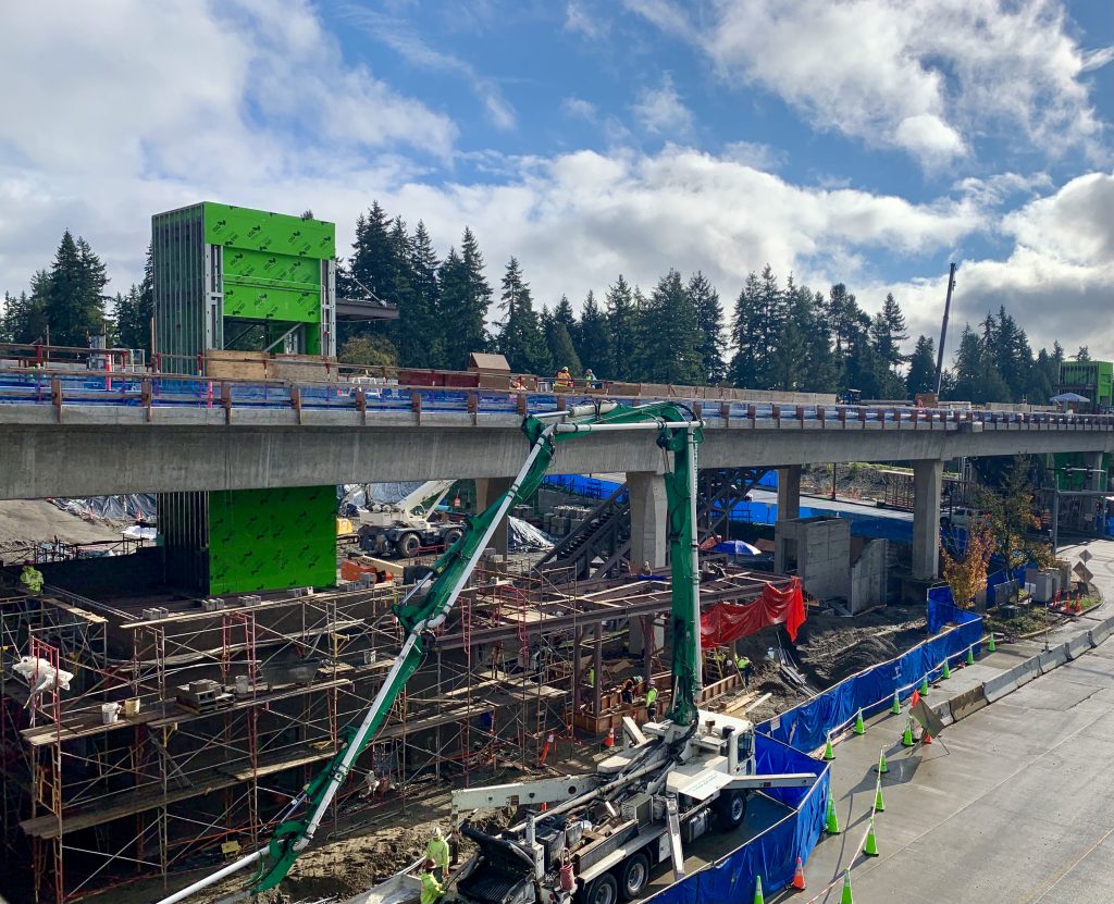 A photo of light rail tracks and a station with elevator in construction. 