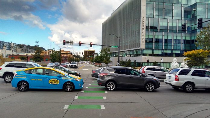 A photo showing cars blocking a marked intersection for pedestrians.