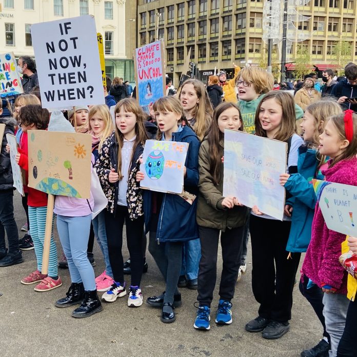 A photo of children holding signs that demand action to fight climate change.