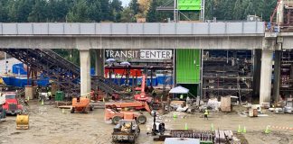 A photo of an active construction site with trailers in front of a light rail line.