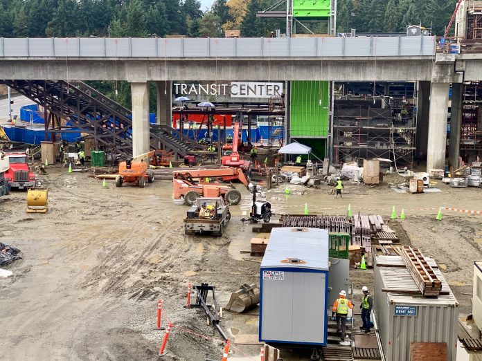 A photo of an active construction site with trailers in front of a light rail line.