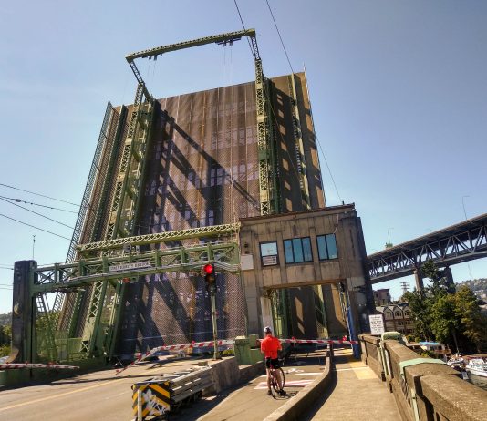 University Drawbridge Closure Highlights Importance of Multimodal Solutions A photo of a raised drawbridge with a cyclists waiting in front of it.
