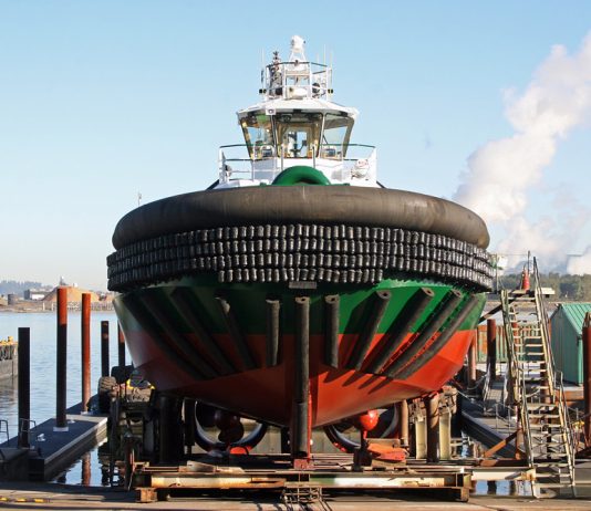 Foss Lost: Shipyard Closure as a Barometer for Resiliency A photo of a black, green, and red tugboat on a platform over the water.