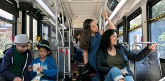 A photo of a mother with three middle school aged children riding a King County metro bus.