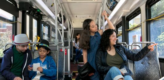 A photo of a mother with three middle school aged children riding a King County metro bus.