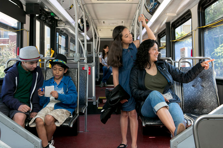 A photo of a mother with three middle school aged children riding a King County metro bus.