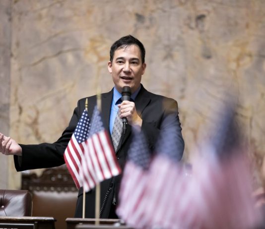 Inslee Taps Hobbs as Secretary of State, Ending His Reign as Senate Transportation Chair Steve Hobbs on the senate floor with American flags in the foreground.