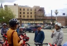 SDOT Director Zimbabwe is Out, What Does This Mean for Seattle Transportation? A group of people wearing bike helmets and standing near bikes listen to a man speaking.