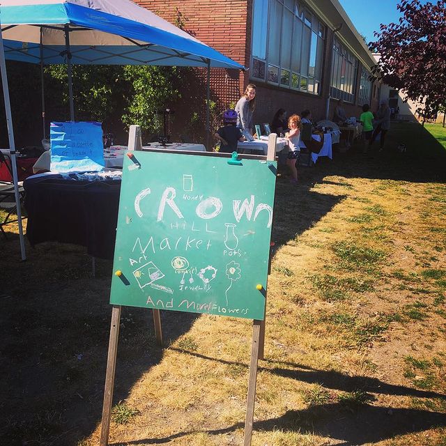 The pop-up Crown Hill Market with a sign with the market's name written in chalk by children. This photo is from 2018.