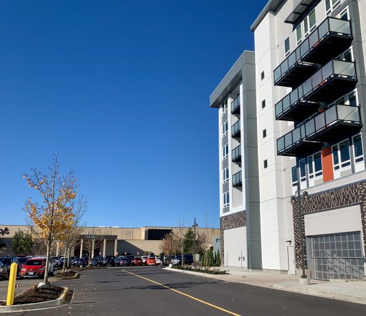 Alderwood Mall Mixes Big Box Stores with Apartment Homes A photo of an apartment next to a parking to with cars and an indoor mall.