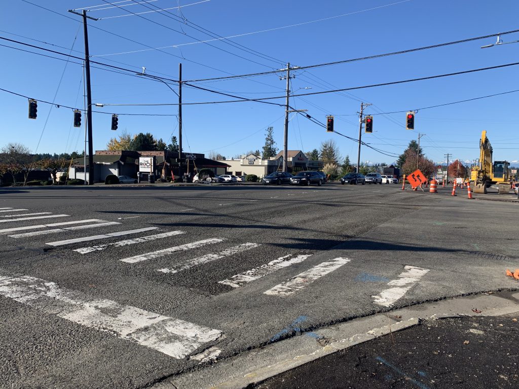 A photo of a wide traffic intersection with a painted pedestrian crossing and construction equipment. 