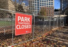 City Hall Park Plans Curtailed by New Seattle Budget A photo of a chainlink fence and a sign reading "park closed" in front a open grassy area.