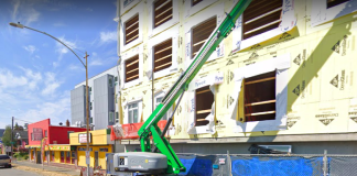 A photo of a green crane in front of an apartment building under construction.