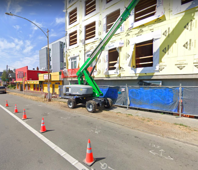 A photo of a green crane in front of an apartment building under construction.
