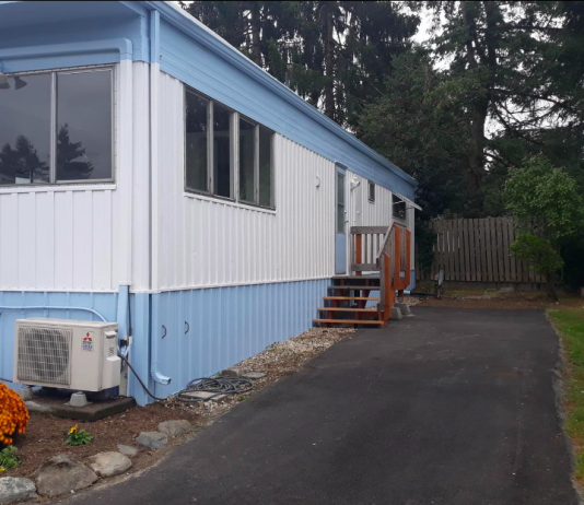 Mobile Home Park Protections to Preserve Up to 11 Acres for Affordable Housing in Bitter Lake A photo of a light blue and white mobile home with a driveway.