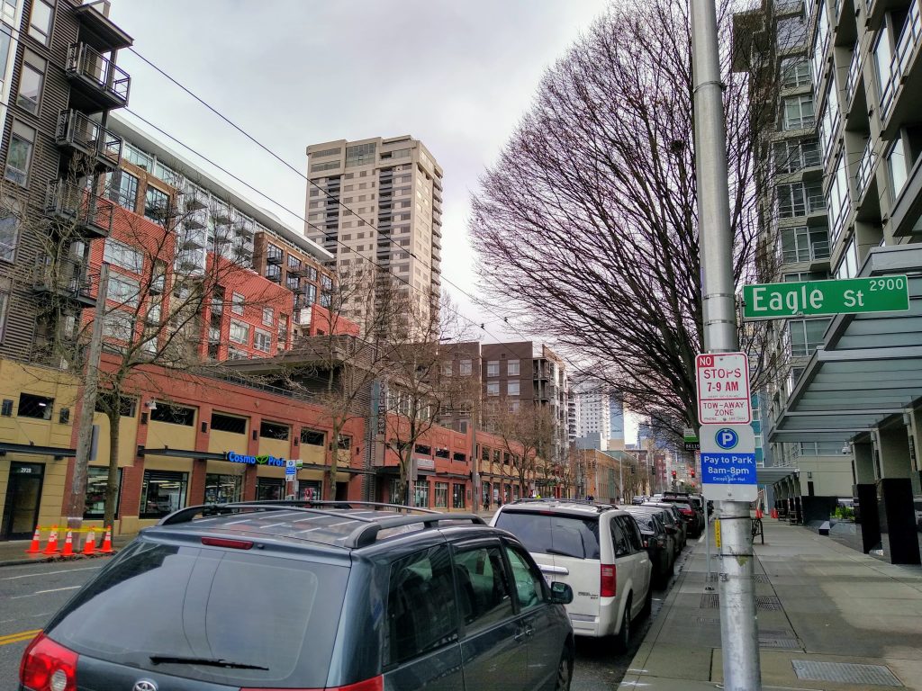 Line of parked cars with an Eagle Street sign at a cross street