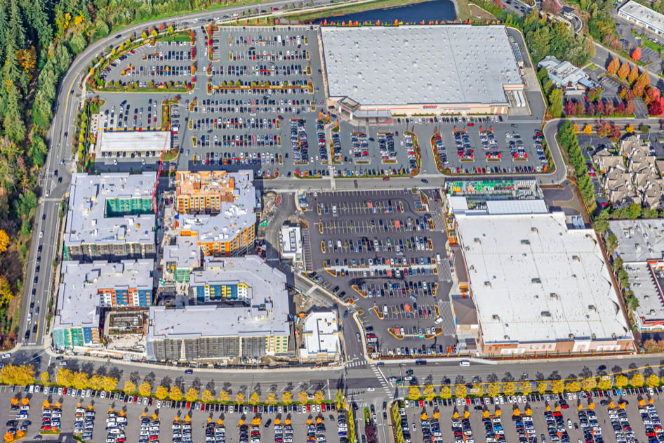 A aerial photo showing a huge development with two big box stores, lots of parking, and a five unit mixed use building under construction. 