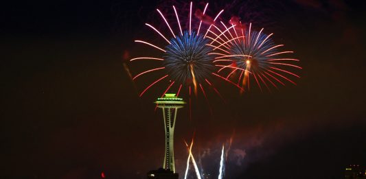 A photo of fireworks at an illuminated space needle