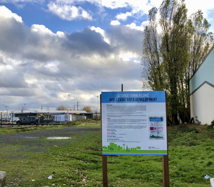 A photo of a sign advertising the Georgetown flume park and trail connection in front of an empty lot.