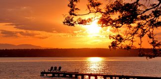 A view of a sunset over a lake with a pier in it.
