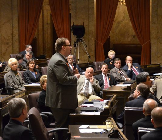 Transpo Notes: No Extra Gas Tax, Metro Staffing Challenges, Governor Makes High Speed Rail Ask A photo of a man wearing a suit in a senate chamber standing and speaking while other people in suits sit and listen.