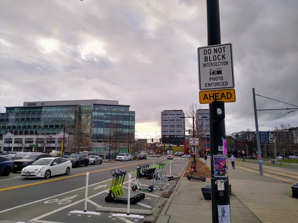 Do Not Block Intersection Photo Enforced Ahead sign in South Lake Union on Valley Street, with bike lane and scooters in bike rack area