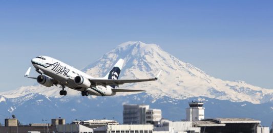 Alaska Airlines plane takes off from Seattle-Tacoma International Airport with Mt. Rainier in the background.