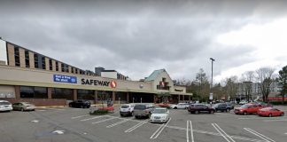 A photo of a low-rise grocery store with a surface level parking lot in front of it.