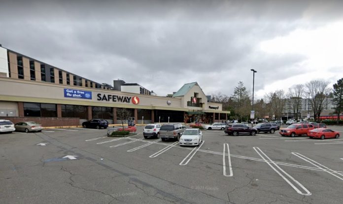 A photo of a low-rise grocery store with a surface level parking lot in front of it.